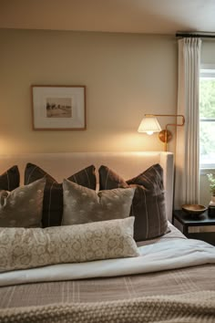 a bed with two lamps on either side of it and pillows on the headboard