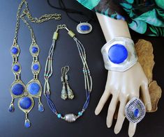 This LOT includes all 6 vintage Afghan jewelry pieces as shown. These pieces are mostly souvenir jewelry - that is jewelry that was made for sale in local souks for sale to travelers as simple trinkets. Not always exquisitely made, but replicas of old tribal jewelry pieces. The Lapis stones on several of them is lapis-composite - which is Lapis-Lazuli that has been pulverized, mixed with resin, and made into reconstituted stone. It is real lapis, just not in its natural state. Includes: ---> 1 Wide Afghan cuff bracelet with large Lapis stone (composite?) and incised band. 7-1/4 inch wrist circumference, including gap. ---> 1 Very-Large oval raised-dome ring with ornate design and lapis stone. Size 12.25 (Very large) ---> 1 Multi-strand Afghan necklace with lapis and adventurine beads. Larg Artisan Handmade Jewelry Vintage Collection, Vintage Decorative Jewelry For Festivals, Vintage Blue Jewelry For Festivals, Blue Vintage Jewelry For Festivals, Vintage Jewelry For Jewelry Making And Festivals, Antique Nickel-free Jewelry For Festivals, Vintage Blue Jewelry With Unique Variations, Decorative Vintage Jewelry For Festivals, Handmade Vintage Blue Jewelry