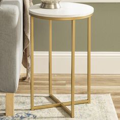 a white and gold end table with a vase on it next to a gray couch