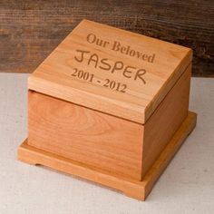 a small wooden box with a dog's paw on the lid and name engraved on it