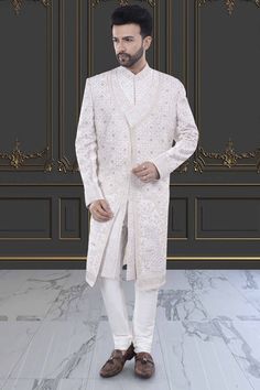 This two-layer sherwani features intricate stones and zardozi, making it perfect for a stylish groom. Step up your traditional attire game with this unique and elegant piece. Elegant Ceremonial Traditional Wear With Stone Work, Eid Traditional Wear With Stone Work, Designer Traditional Wear With Naqshi Detailing, Designer Long Traditional Wear With Naqshi Detailing, Ceremonial Long Sherwani With Resham Embroidery, Traditional Formal Sets With Stone Work, Designer Long Traditional Wear With Naqshi, Elegant Sherwani With Dabka Work And Traditional Drape, Formal Long Sherwani With Intricate Embroidery