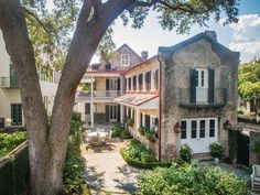 the house is surrounded by many trees and bushes, with an outdoor seating area in front