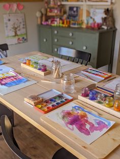 the table is covered with watercolors and other art supplies for children to use