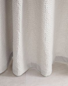 a close up of a white curtain on a window sill in a room with tile flooring