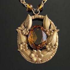 Vintage Art Deco gold plated orange Czech glass flowers and foliage pendant necklace. Good condition with signs of age and wear. The chain has lost much of its plating. Dark spot on one of the leaves on the pendant. Necklace measures 15" long Pendant measures 1.9" x 1.5" Vintage Oval Pendant Necklaces With 17 Jewels, Vintage Amber Oval Pendant Jewelry, Vintage Gold Jewelry With Large Pendant, Antique Bronze Flower Pendant Necklace, Gold Flower Pendant Costume Necklace, Antique Necklaces With Large Flower Pendant, Art Deco Gold Necklace With Large Pendant, Victorian Gold Necklace With Flower Pendant, Ornate Gold Collectible Necklace