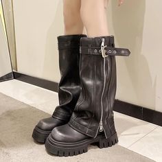 a woman wearing black boots with zippers on the bottom and side, standing in front of a mirror