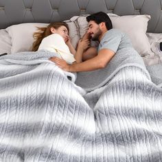 a man and woman laying in bed under a blanket