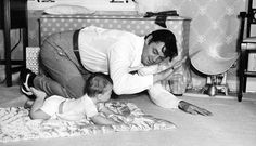 a man kneeling down next to a baby on the floor