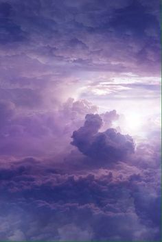 the sky is filled with purple clouds and bright sunbeams in the distance, as seen from an airplane window