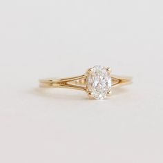 a yellow gold engagement ring with an oval cut diamond in the center, on a white background