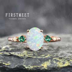 a white opal and green diamond ring on top of a rock with the words firstmet