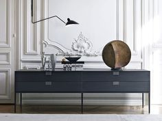 a black and white table with a lamp on it next to a dresser in a room