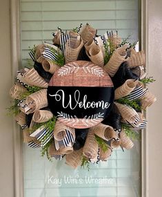 a welcome wreath with burlocks and bows hanging on the front door to greet guests