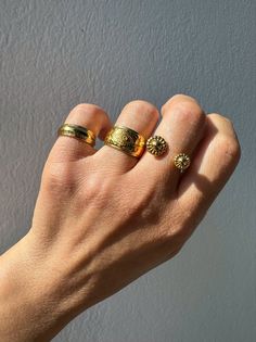 Elevate your style with our exquisite collection of gold stacking rings, exclusively available at Christina Christi Store. Crafted to perfection, this set features a medium-width ring with engraved edges, a mesmerizing evil eye design on the middle ring, and a uniquely stunning ring with two spheres at the edges. Each ring is slightly adjustable for a comfortable fit on any finger. With a diameter of 17mm (0.67'') or US size 7, these rings are versatile for any occasion. Please note that each ri Yellow Gold Brass Stackable Rings, Gold Brass Rings With Round Band, Yellow Gold Brass Stackable Promise Rings, Elegant Gold Stackable Flower Ring, Gold Brass Rings Fine Jewelry, Gold Brass Rings In Fine Jewelry Style, Gold Brass Fine Jewelry Rings, Gold Midi Rings Of Recycled Gold, Gold Stackable Ring Jewelry