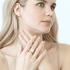 a woman with blonde hair wearing a ring and looking off to the side while holding her hands on her chest