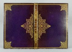 an open purple and gold book on a white surface