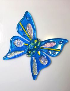 a blue and yellow flower brooch sitting on top of a white table next to a wall