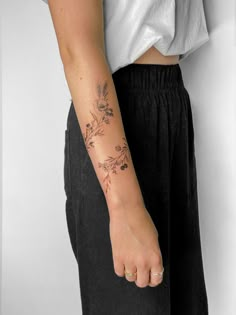 a person with a flower tattoo on their left arm and the other hand behind them