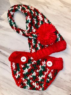 two red and green knitted items sitting on top of a marble counter next to each other