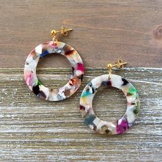 a pair of colorful earrings sitting on top of a wooden table