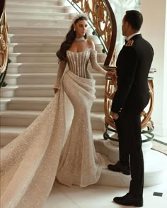 a man and woman standing next to each other in front of some stairs wearing formal wear