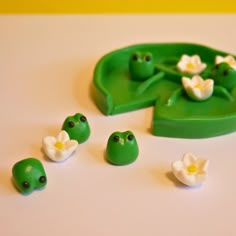 there is a green frog toy with white flowers on it