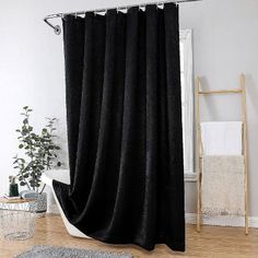 a black shower curtain in a bathroom with wood flooring and white walls, along with a rug on the floor