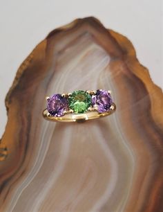 CJ122787AGRT Three stone Maine gemstone ring. Vibrant tourmaline and amethyst are set in this timeless 10k yellow gold three stone ring mounting. Green tourmaline is .60ct, Amethyst total weight is 1.3cts. Currently the ring is size 6.5 but we can resize at no extra charge, please specify ring size at checkout if needed. Retail Jewelry, Amethyst And Diamond Ring, Ring Mountings, Three Stone Ring, Tourmaline Jewelry, Tourmaline Ring, Custom Jewelry Design, Three Stone Rings, Yellow Gold Ring