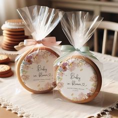 two cookies wrapped in plastic sitting on top of a table next to each other with bows