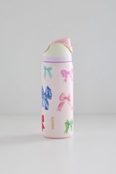 a pink insulated water bottle with bows on the front and side, sitting on a white surface