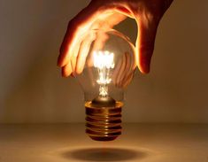 a person is holding a light bulb with their hands on the top and bottom of it