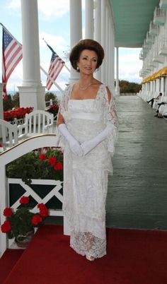 a woman standing on a red carpet next to white pillars