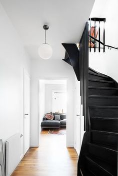 a black and white staircase leading up to a living room with a couch on the other side