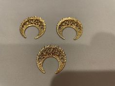 three pieces of gold broochies sitting on top of a table