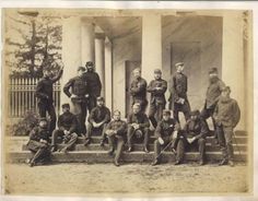 an old black and white photo of men in uniforms posing for a group photograph on steps