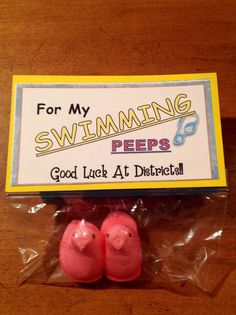 two pink pees sitting on top of a plastic bag next to a sign that says, for my swimming pees good luck at district