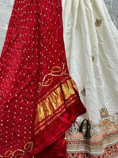 This exquisite ensemble includes a white color gadwal silk lehenga with intricate thread work, sequin work, stonework, and Lakhani work, paired with a similar color gadwal silk choli adorned with the same detailed embellishments. To complete the look, a vibrant red gajji silk dupatta with bandhani work adds a pop of color and elegance.
This lehenga choli set includes the semi-stitched white lehenga that can be customized up to 42 inches, along with an unstitched 1-meter choli material for the pe White Sharara With Cutdana For Diwali, White Sharara With Cutdana For Navratri, White Cutdana Sharara For Navratri, Festive White Cutdana Sharara, White Silk Anarkali Set, Navratri Anarkali Set With Pallu In Chinon, White Sharara With Cutdana In Traditional Drape, White Chanderi Sharara With Traditional Drape, White Kundan Lehenga With Cutdana