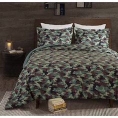 a bed covered in a green and brown camouflage print comforter set with two pillows