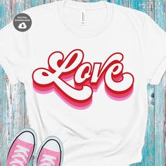 a t - shirt with the word love in red and pink on it next to sneakers