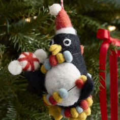 a penguin ornament hanging from a christmas tree with red and white ornaments on it