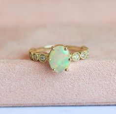 Gold opal & diamond engagement ring. Vintage inspired oval-cut Ethiopian or Australian opal ring with accent white diamonds and filigree detail. The design can be made with gemstones of your choosing. If you would prefer a custom item, please contact us before purchase. Details Main stone: oval-cut welo Ethiopian or Australian opal Size: approx. 9x7mm Accent stones: round-cut white diamonds Size: approx. 1.35mm (10) Quality: clarity grade VS, color grade F-G, conflict-free Band size: approx. Ethiopian Opal Oval Ring For Wedding, Opal Rings With Diamond Accents, Oval Shaped, Oval Opal Rings With Diamond Accents, Oval Ethiopian Opal Ring For Anniversary, Opal Oval Diamond Ring With Gemstone, Oval Opal Diamond Ring With Gemstone, Oval Opal Diamond Ring With Gemstone Details, Heirloom Oval Opal Ring With Diamond Accents, Oval Opal Diamond Ring