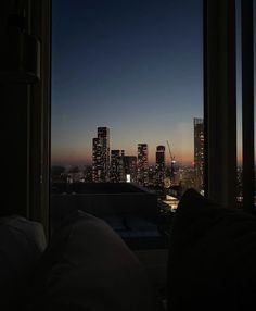 the city skyline is lit up at night as seen from an apartment window with no curtains