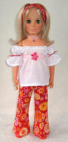 a doll with blonde hair wearing red pants and a white top, standing in front of a white background