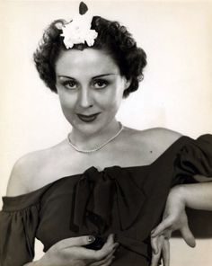 an old black and white photo of a woman with a flower in her hair wearing a dress