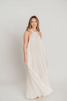 The Maren Pleated Halter Maxi Dress is an exquisite statement piece that exudes Greek-inspired elegance. Crafted from a lightweight cream fabric, it features a flattering drape, romantic silhouette, and classic pleating details. An exquisite choice for any special occasion. FIT: Runs true to size. MODEL: Mackenzie is 5’7” / 130lb / wearing a small. Heather is in her third trimester, wearing a small. MATERIAL: GARMENT DETAILS: Maxi dress with pleated details, halter neckline, and open back. MEASUREMENTS: (Note: flat lay measurements are approximate. Double the measurement for the full circumference of the garment). Spring Pleated Pre-draped Midi Dress, Cream Pre-draped Evening Dress, Elegant Pleated Bridesmaid Maxi Dress, Elegant Pleated Maxi Dress For Bridesmaids, Chic Wedding Maxi Dress With Pleated Back, Elegant Beige Pleated Dress, Chic Draped Maxi Dress With Pleated Back, Feminine Pleated Maxi Dress, Cream Flowy Maxi Dress In Feminine Style