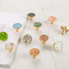 a bunch of different colored knobs sitting on top of a white table next to a book