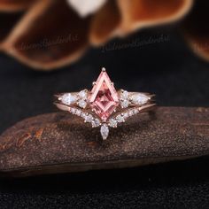 a pink diamond ring sitting on top of a rock