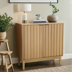 a wooden cabinet sitting next to a lamp and potted plant