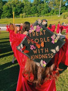 a group of people in red graduation gowns and caps with writing on them that says treat people with kindness