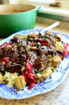 a blue and white plate topped with pasta and meat